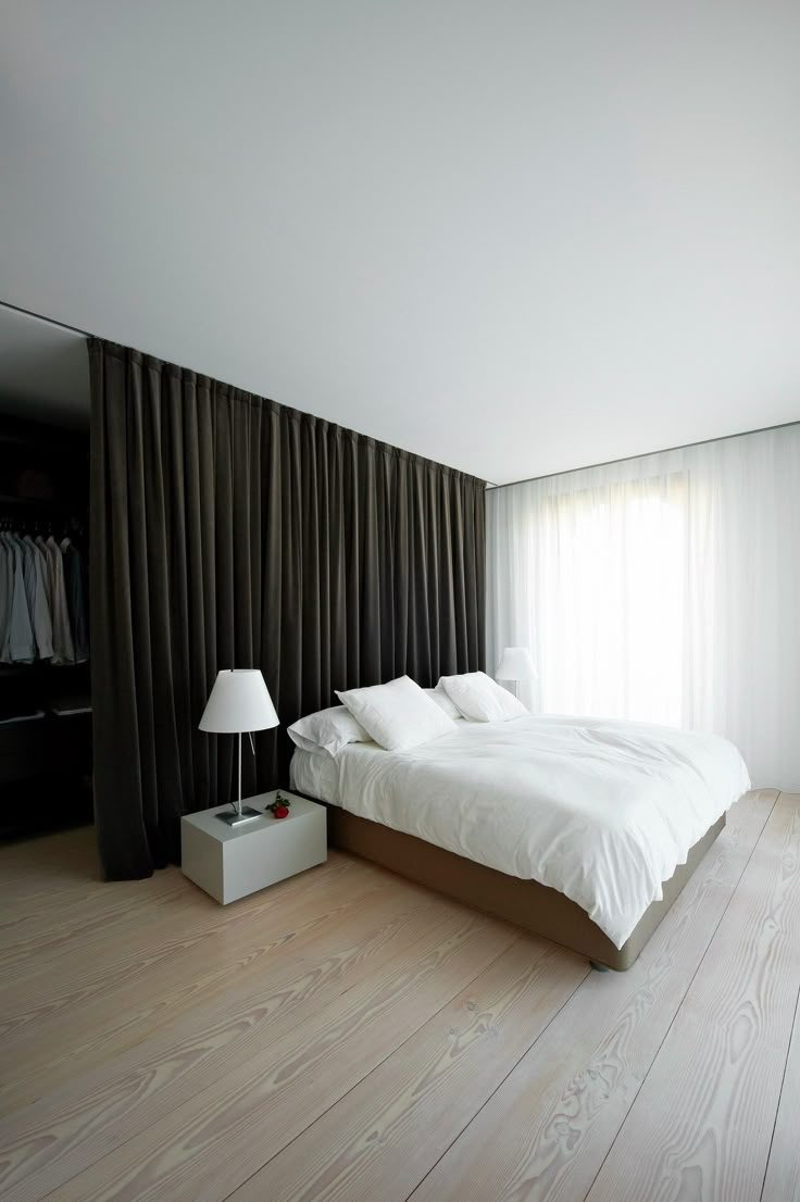 a large bed sitting next to a lamp on top of a wooden floor in a bedroom