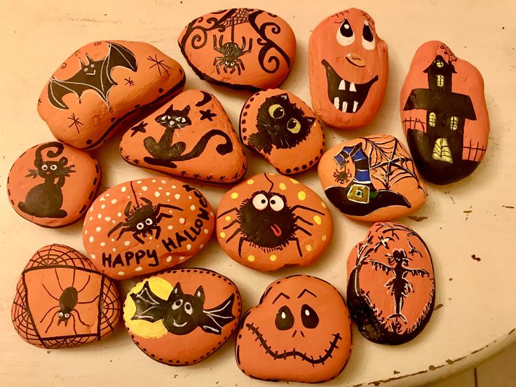 many decorated rocks are sitting on a table with pumpkins and bats painted on them