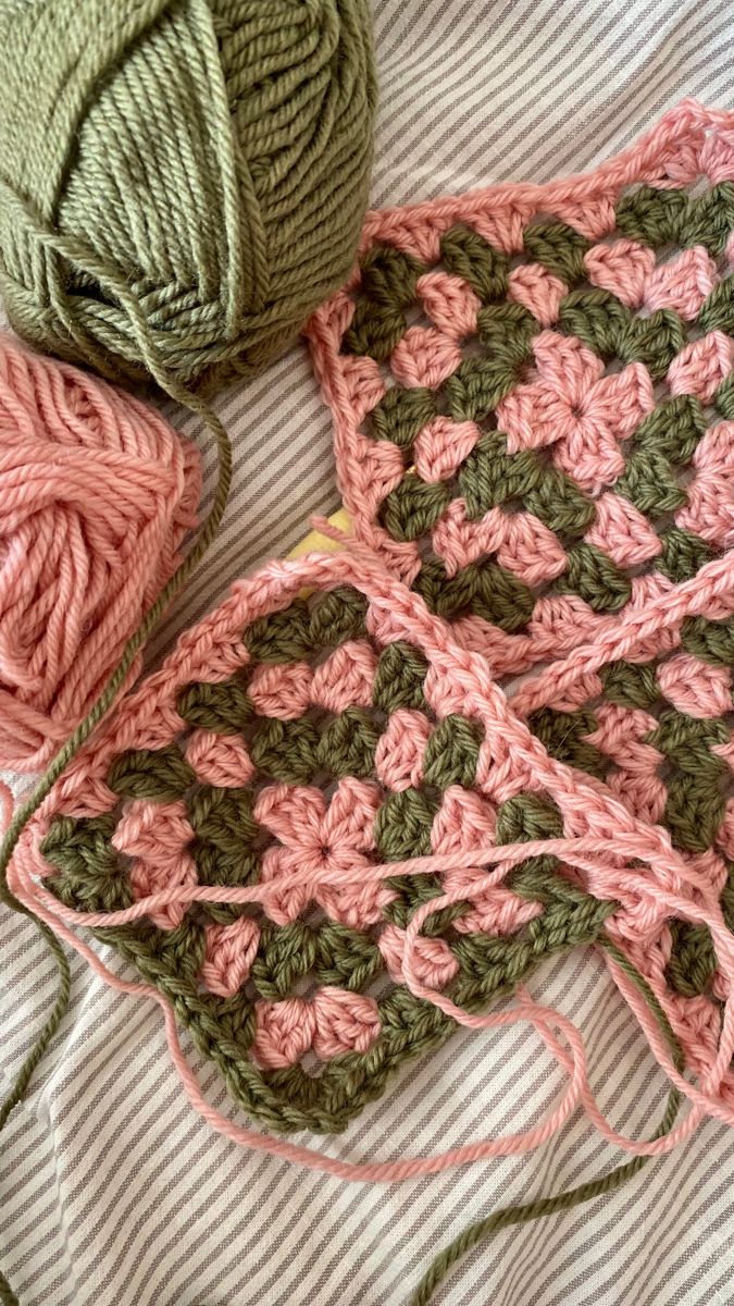 two balls of yarn sitting next to each other on top of a bed with pink and green crocheted afghans