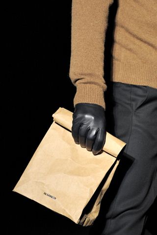 a person in black gloves holding a brown paper bag