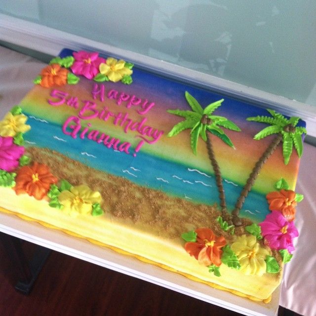 a birthday cake decorated with flowers and palm trees