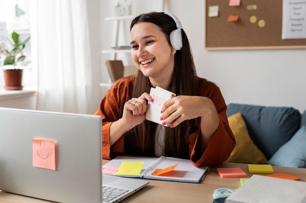 a woman sitting at a desk with headphones on and holding a piece of paper