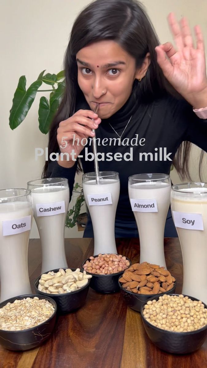 a woman sitting at a table filled with milk and nuts in front of her face