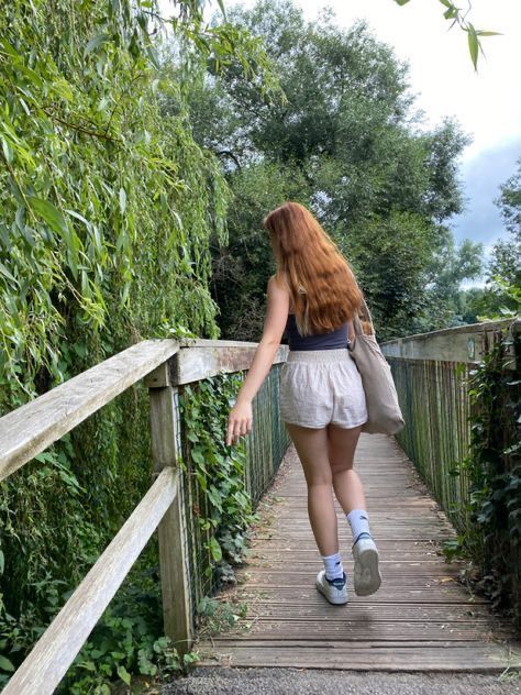 a woman walking across a wooden bridge