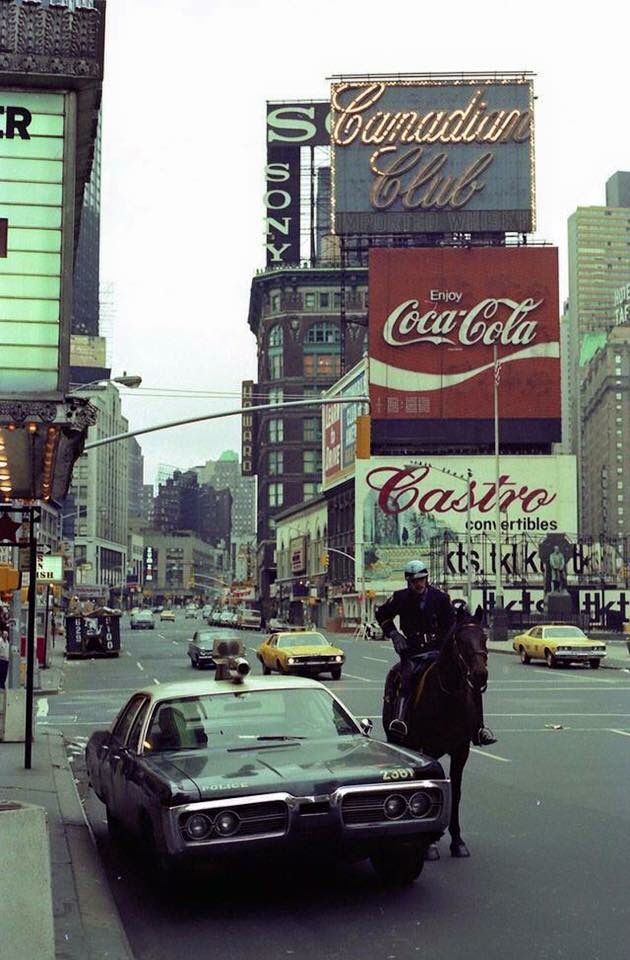 a man riding a horse next to a car in the middle of a busy city