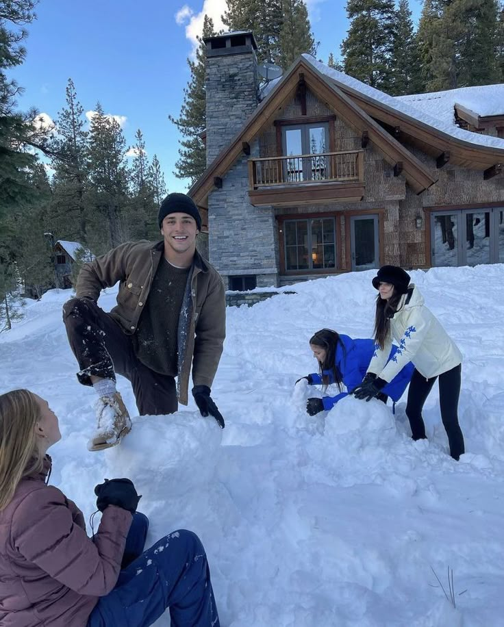 three people are playing in the snow near a house