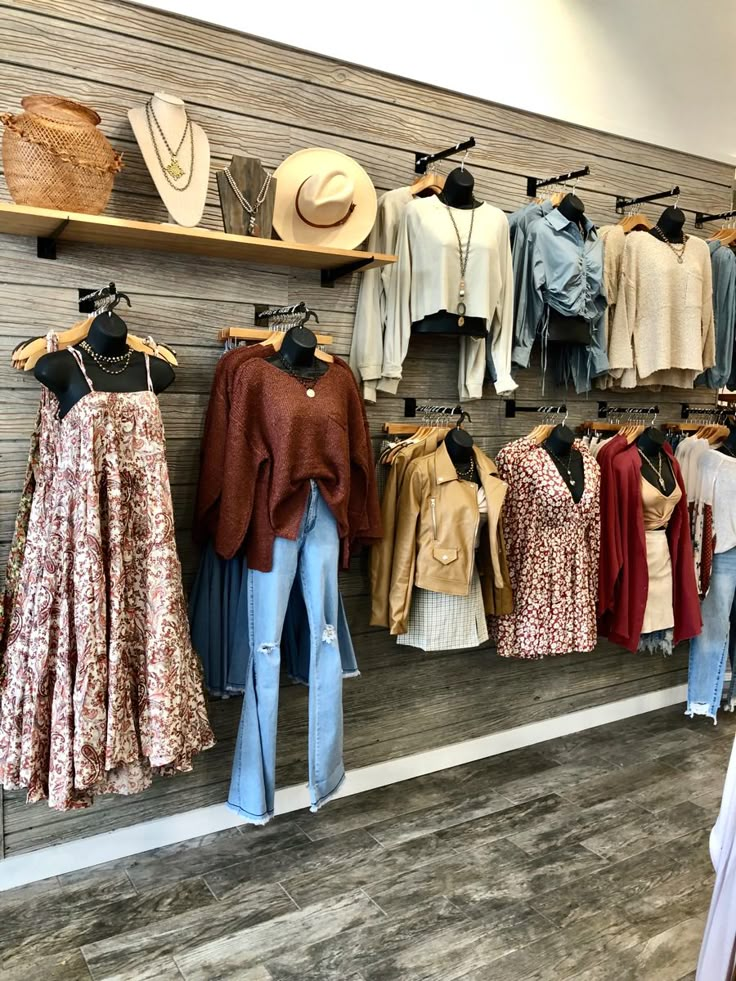 clothes are hanging up on the wall in a clothing store with hats and other items