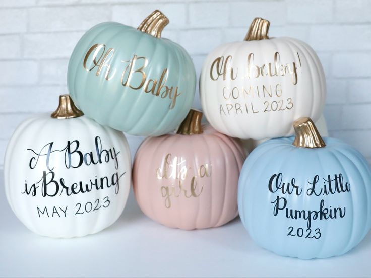 four painted pumpkins with the names of babies and their parents in gold lettering on them