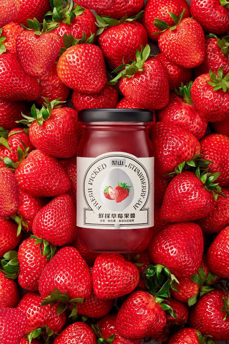 a jar of strawberry jam surrounded by strawberries