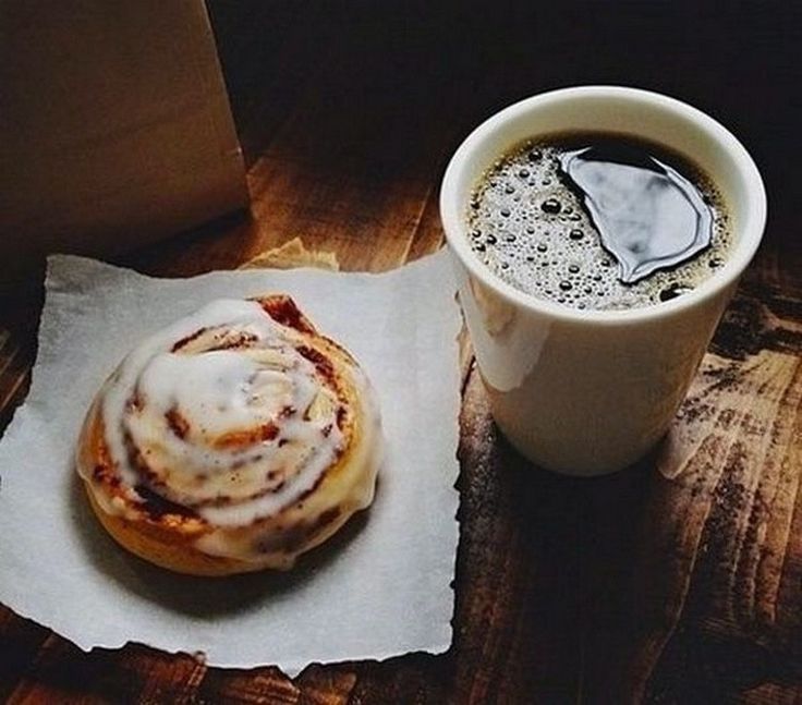 a cup of coffee sitting next to a pastry on top of a piece of paper