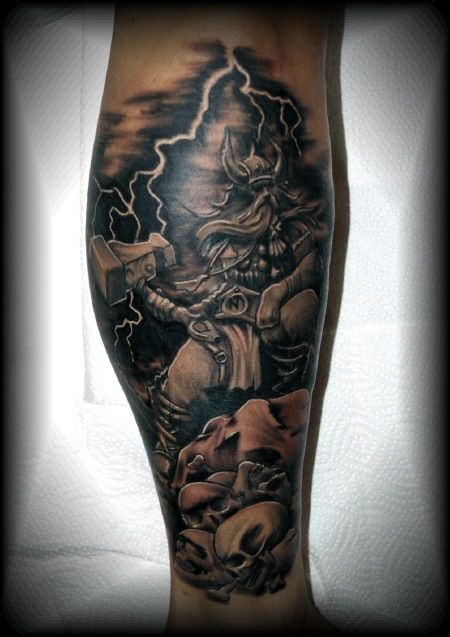 a man's leg with an image of a demon on it and lightning in the background