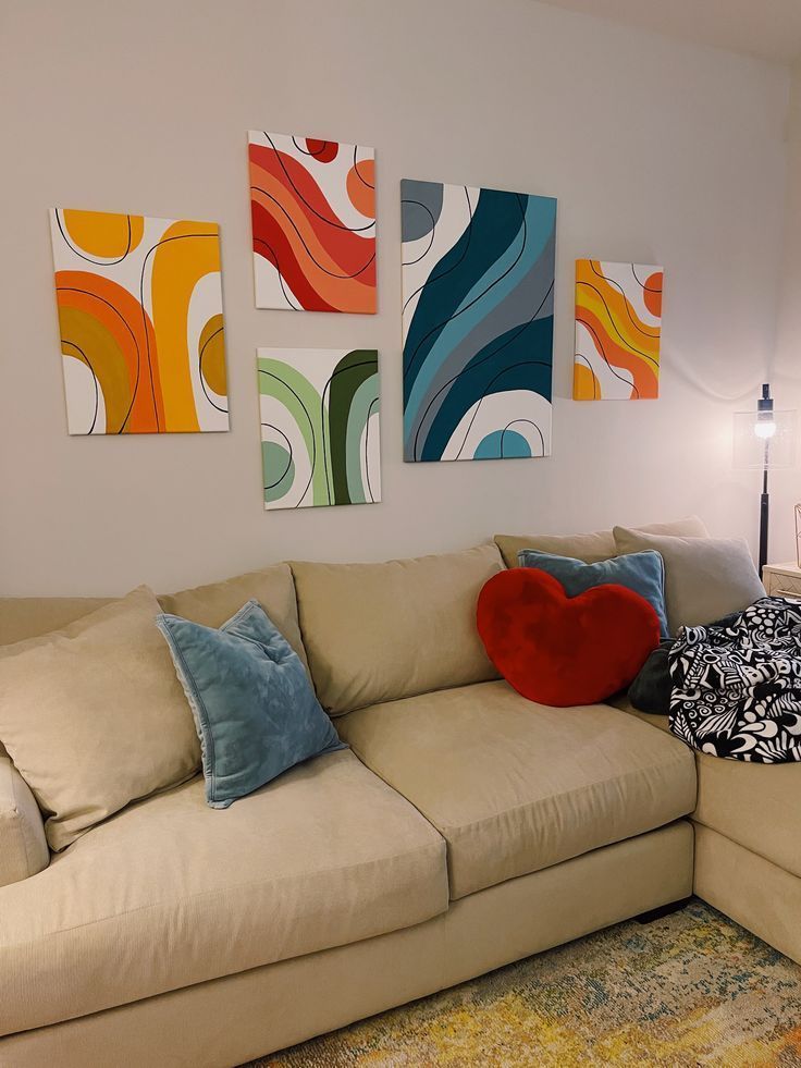 a living room filled with furniture and paintings on the wall above it's couch