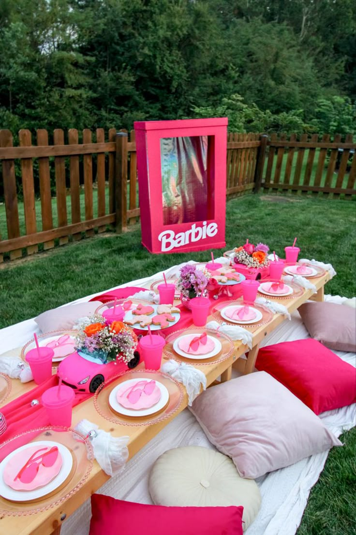 a table set up with pink plates and place settings for a barbie themed birthday party