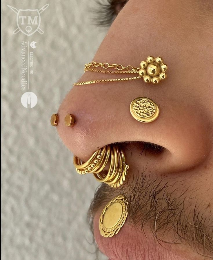 a close up of a mans nose with gold jewelry on it's nose and behind his ear