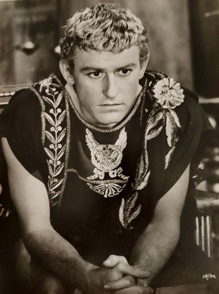 a man sitting at a table with his hands on his knees and looking into the camera