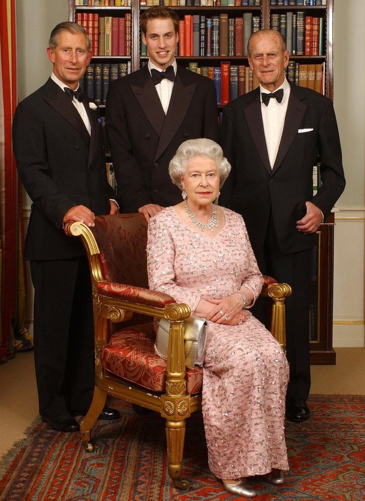 three men in tuxedos pose for a photo with an older woman on a chair