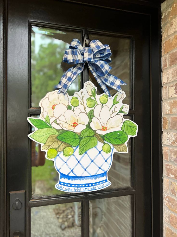 a blue and white vase filled with flowers on top of a glass door frame next to a brick wall