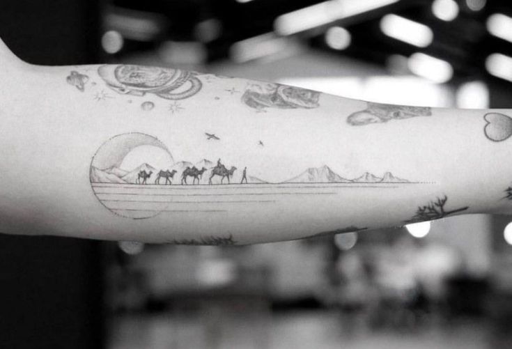 black and white photo of a person's arm with tattoos on it, including camels