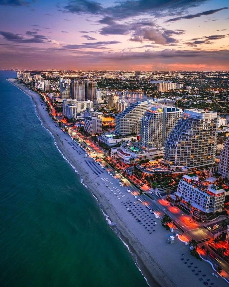 an aerial view of the beach and hotels at dusk