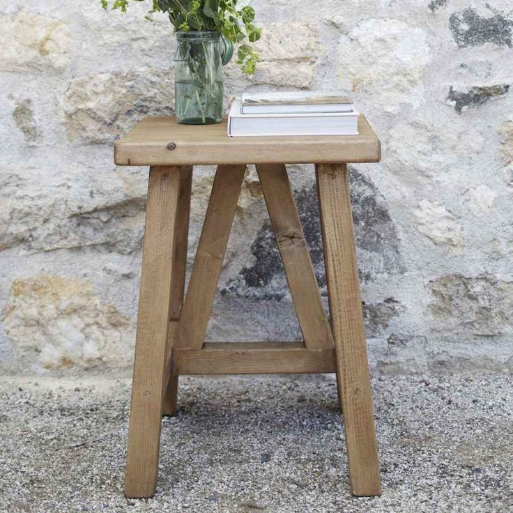 a small wooden table with flowers in a vase on it and a book next to it