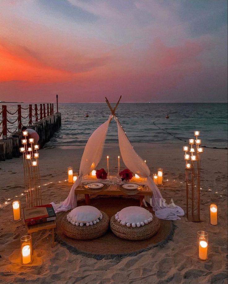 a table set up on the beach with candles