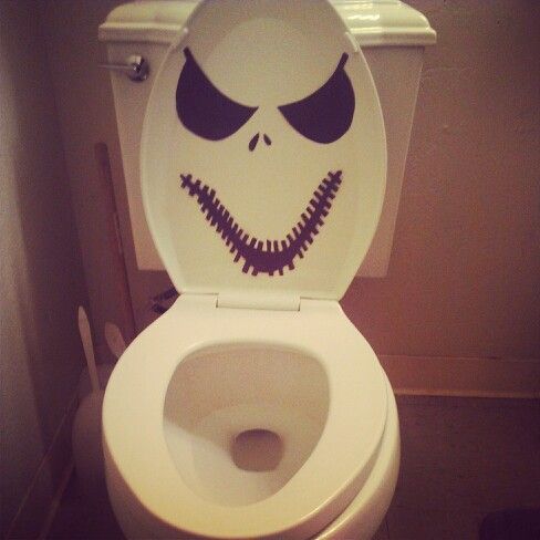 a white toilet with the lid up and an image of a creepy face painted on it