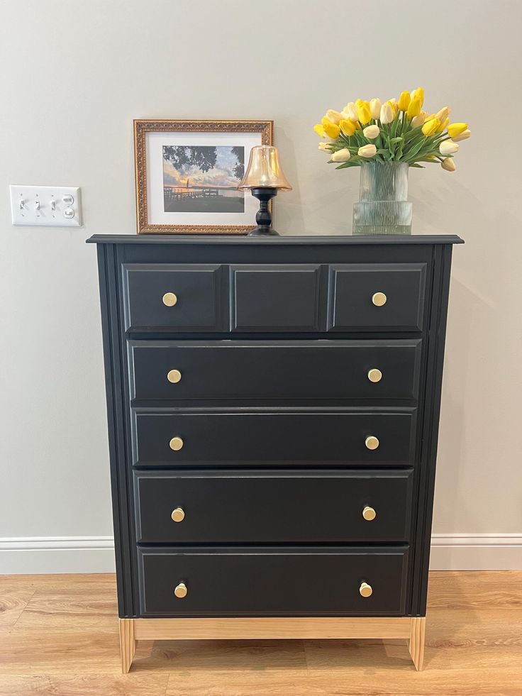 a black dresser with yellow flowers on top