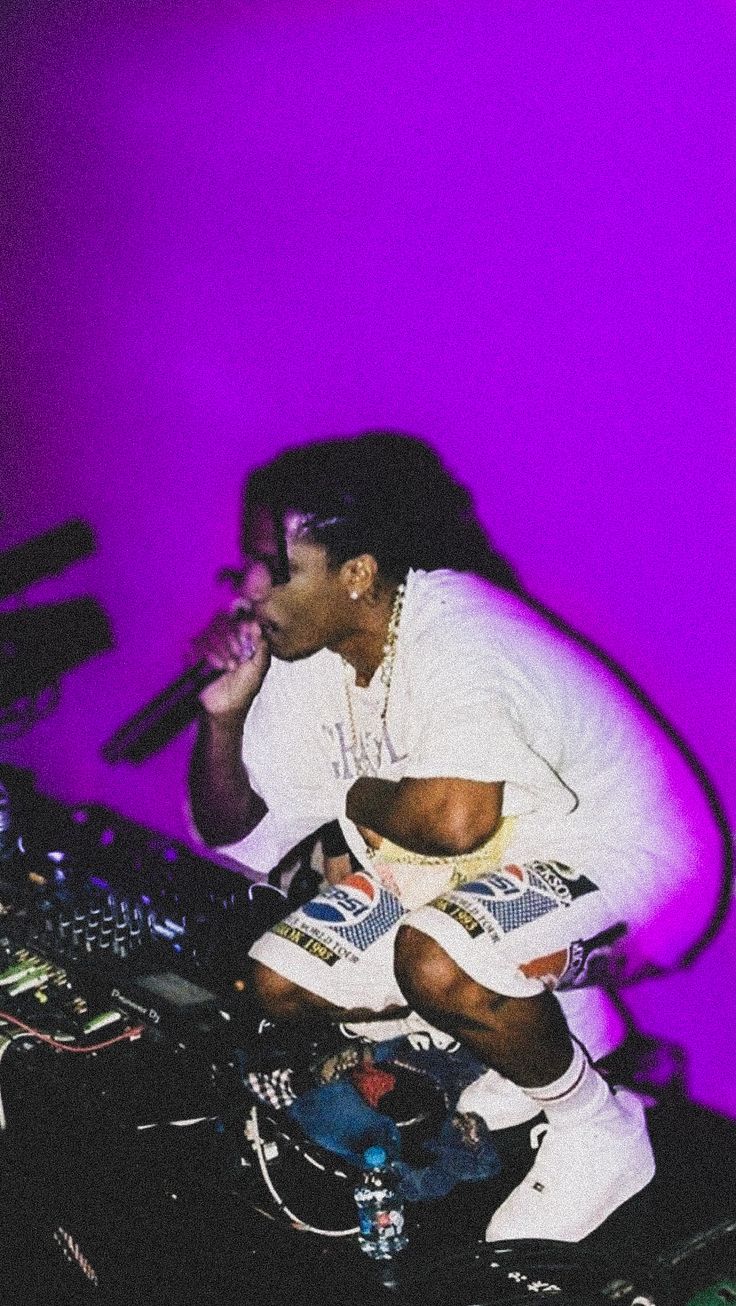 a man sitting on top of a dj's turntable in front of a microphone