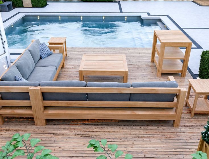 a couch and table sitting on top of a wooden deck next to a swimming pool