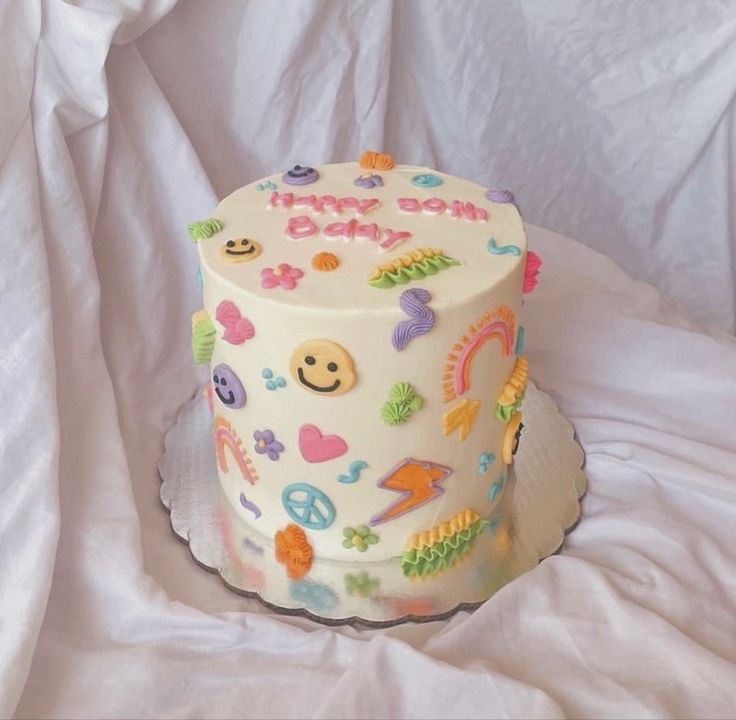 a white cake with colorful designs on it sitting on top of a white table cloth