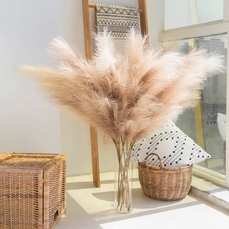 a vase filled with dry grass sitting next to a window sill on top of a white floor