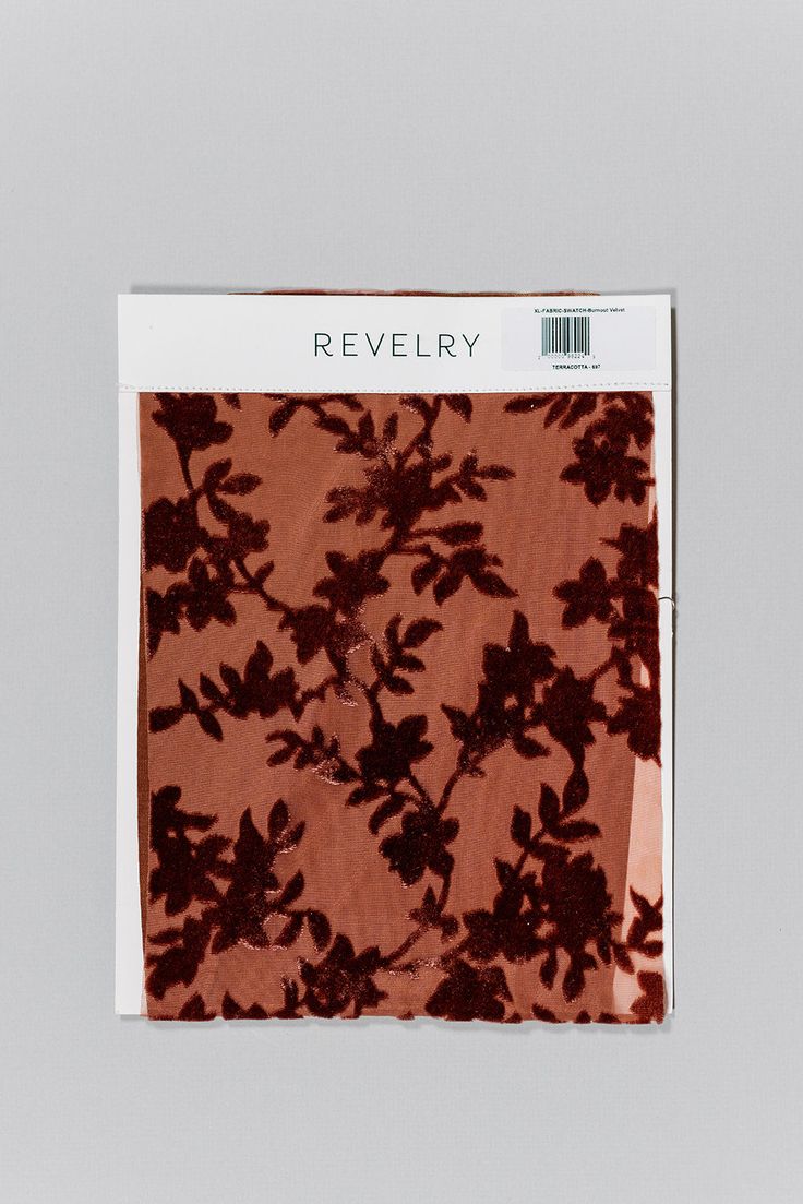 a piece of cloth with flowers on it in red and brown colors, sitting on a white surface