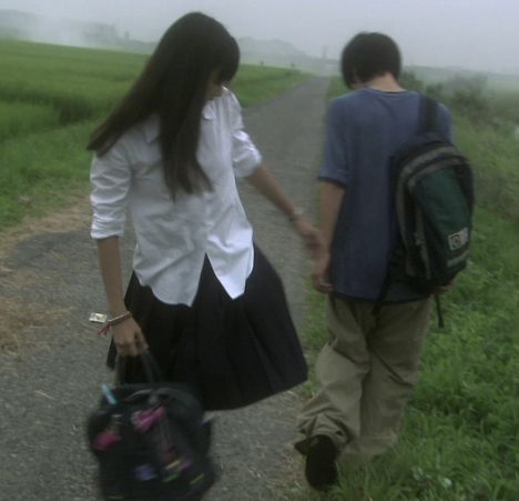 two people walking down a dirt road with backpacks on their back and one person holding the other's hand