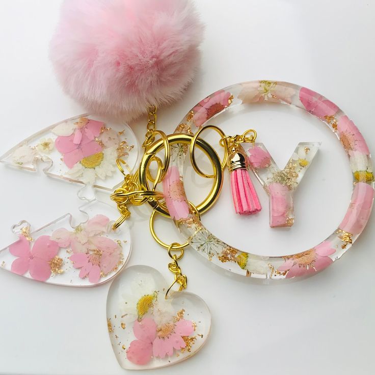 the key chain is decorated with pink flowers and gold trimmings, including a heart shaped acrylic charm