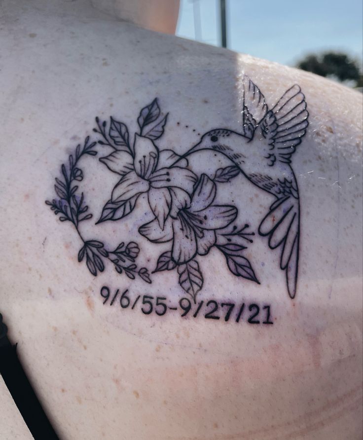 a tattoo on the back of a woman's shoulder with hummings and flowers