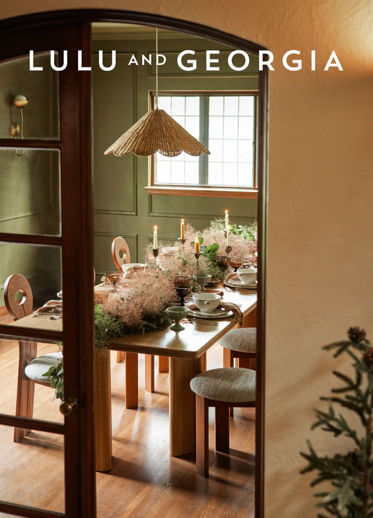 the dining room table is set with flowers, candles and plates in front of an open doorway