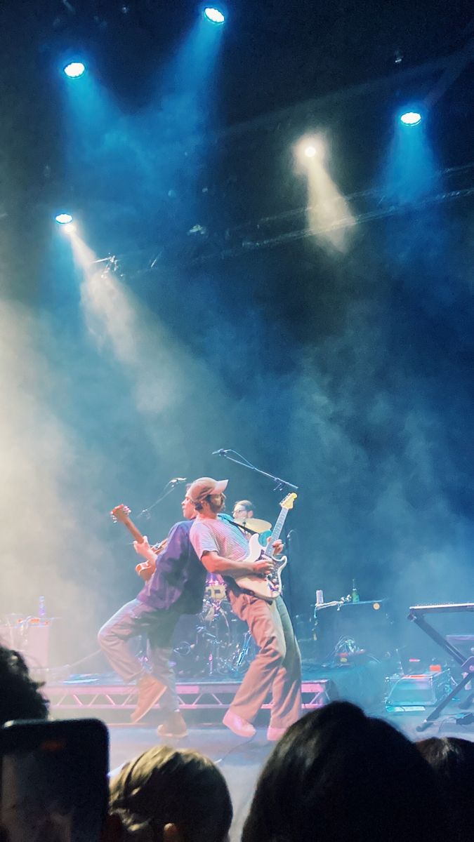 two men on stage playing guitar and singing into microphones in front of an audience