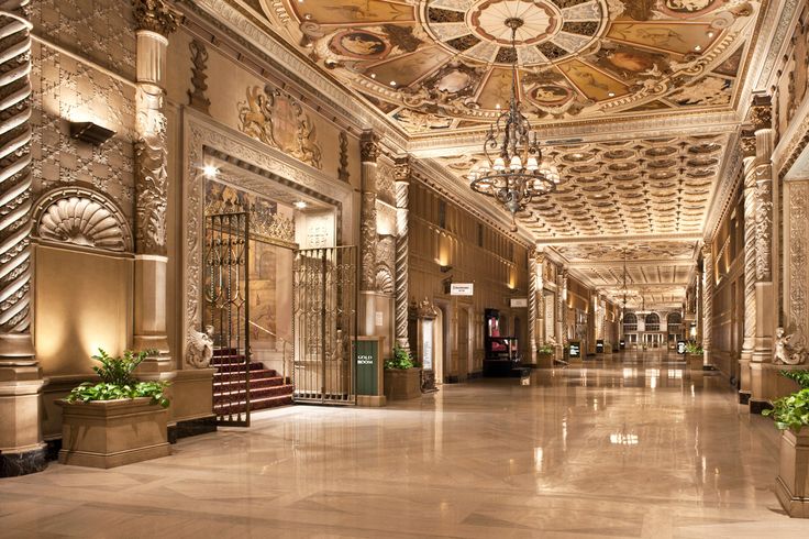 an ornately decorated lobby with chandeliers and planters on either side of the entrance