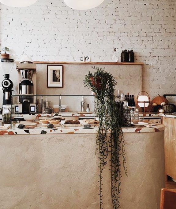 a counter with some plants on it in front of a brick wall and two lights