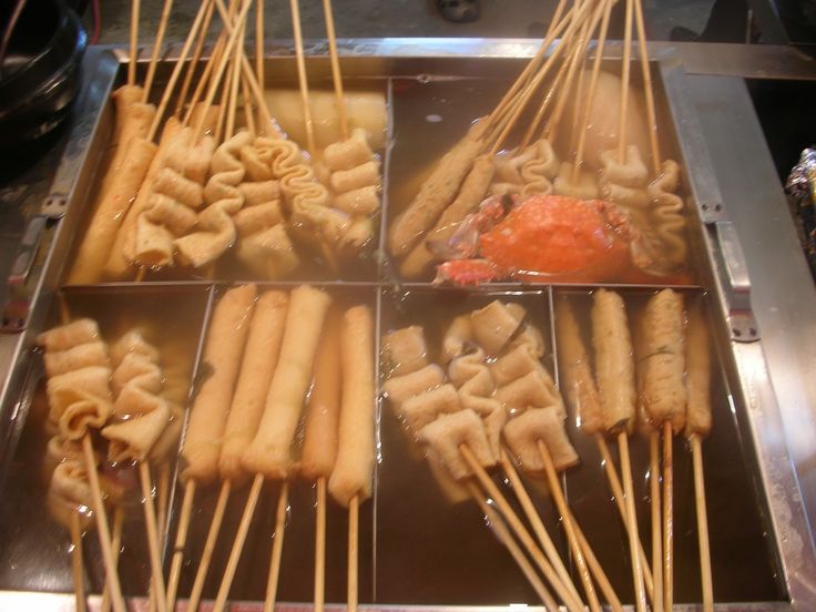 several skewers of food sitting on top of a metal pan covered in liquid