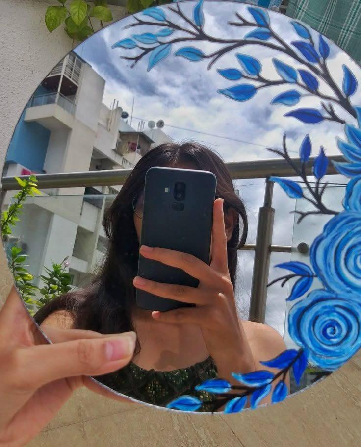 a woman taking a selfie in front of a mirror with blue flowers on it