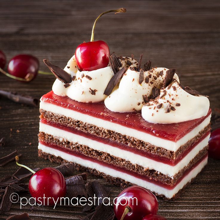 a piece of cake with cherries on the top and chocolate shavings around it