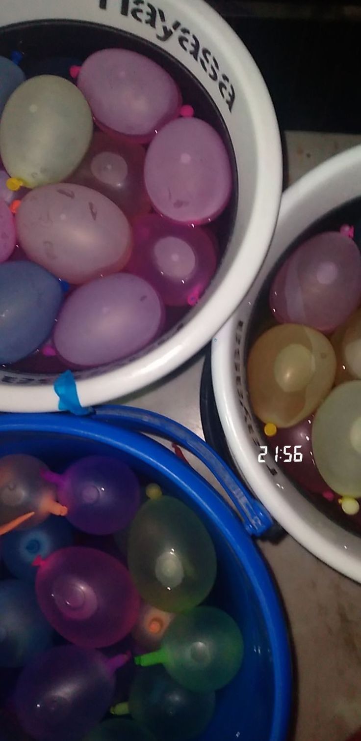 two buckets filled with balloons sitting on top of a table