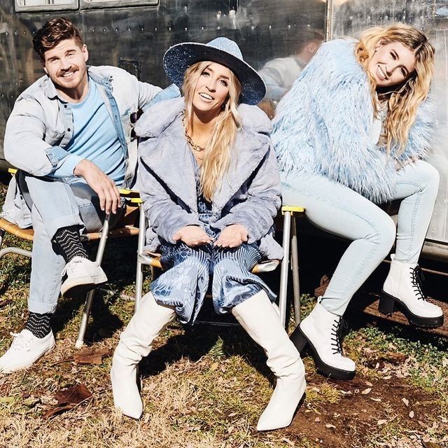 three people sitting on chairs in front of a trailer