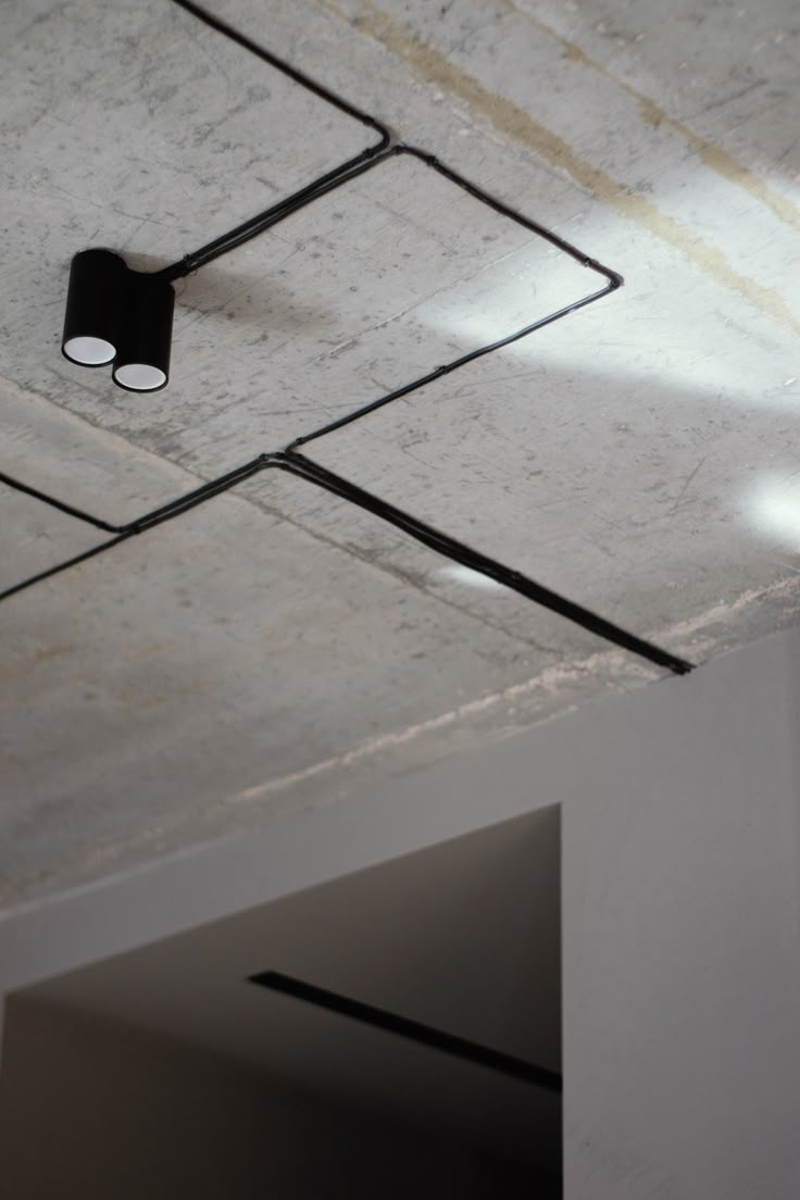 a ceiling light that is hanging from the ceiling in a room with concrete walls and flooring