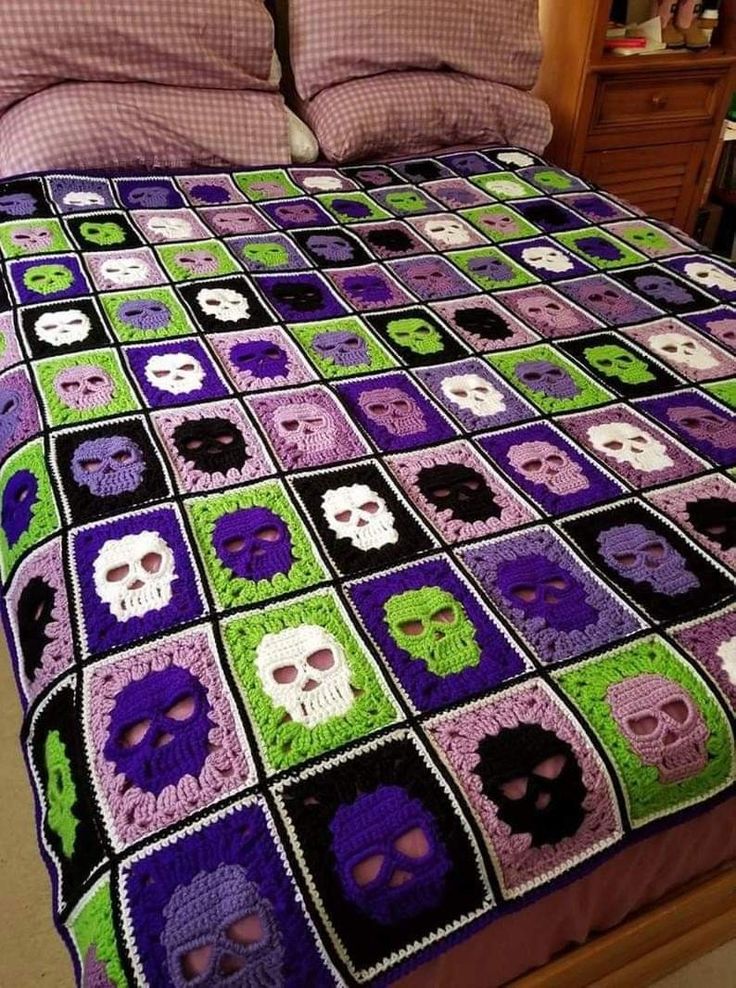 a crocheted blanket with skulls and squares on the bottom is made into a bed