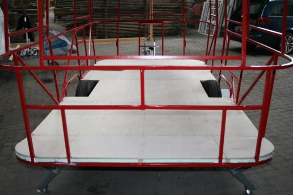 a red and white cart sitting on top of a brick floor next to a building