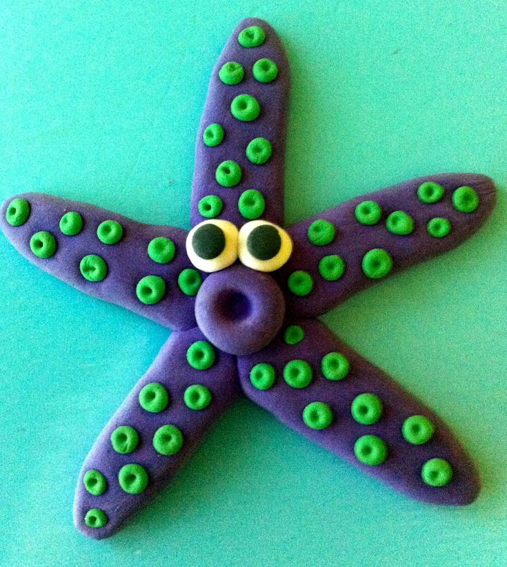 a purple and green starfish with googly eyes on it's face sitting on a blue surface