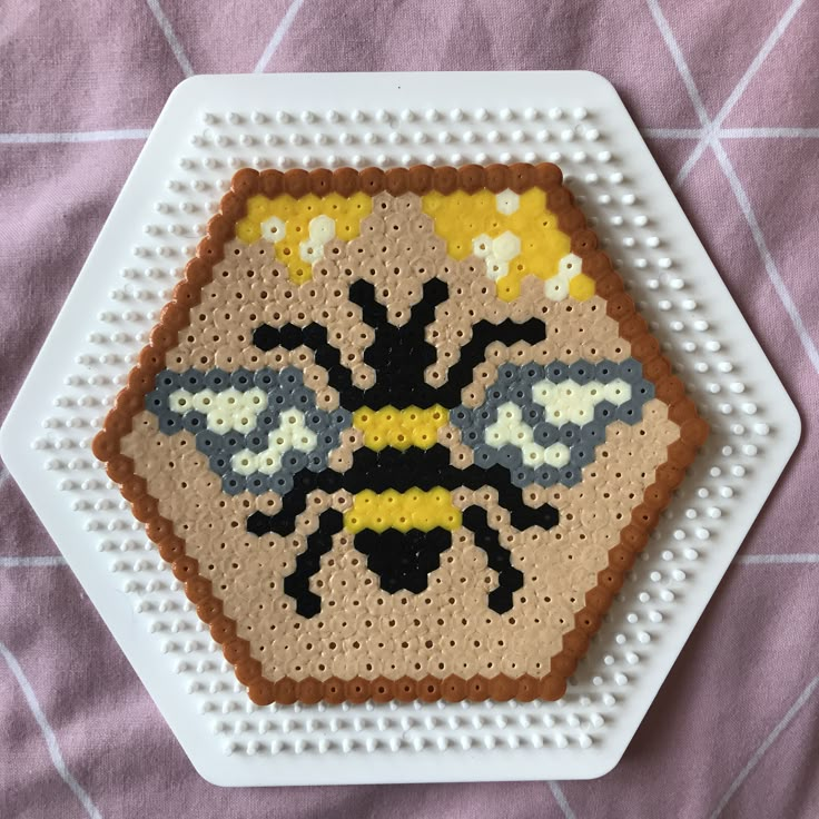 a cross stitch bee on a white plate