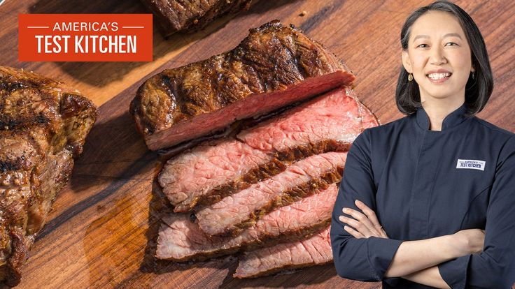 a woman standing in front of steaks on a wooden cutting board with the words america's test kitchen